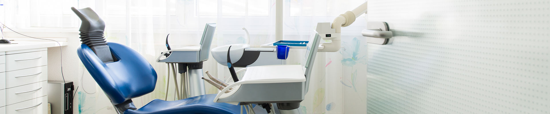 Blick in ein Behandlungszimmer mit blauem Behandlungsstuhl